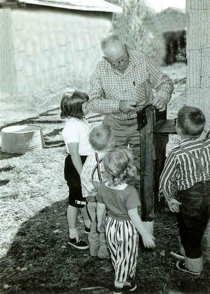 My grandfather sharpening a saw as grandchildren look on.  I'm second from the left. 